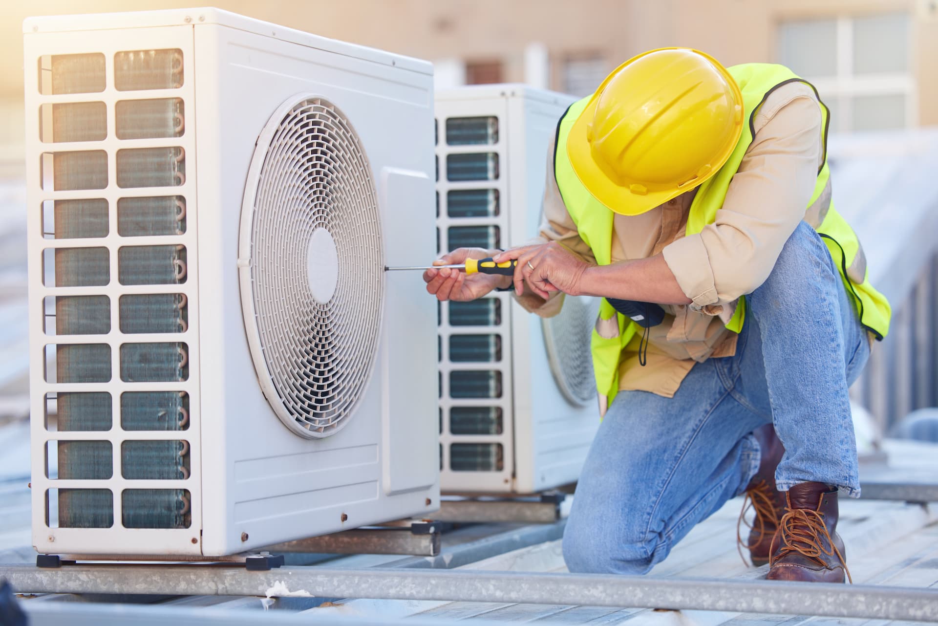 Contractor working kneeling down to work on a rooftop AC unit
