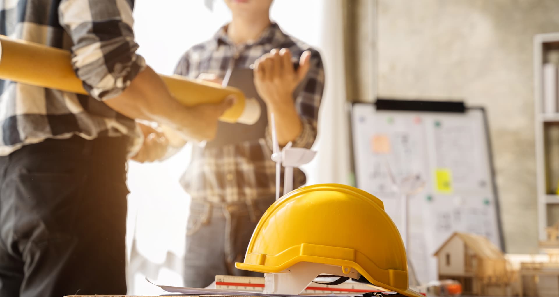 Two contractors review and discuss construction documents in office.