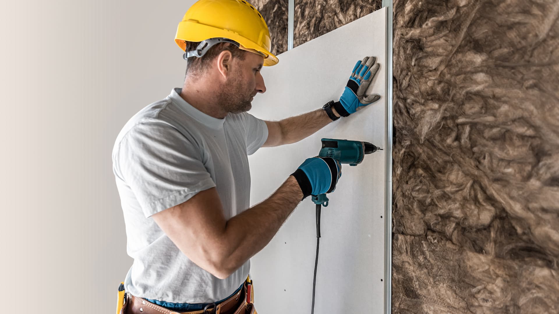 Drywall contractor installing drywall over insulated wall