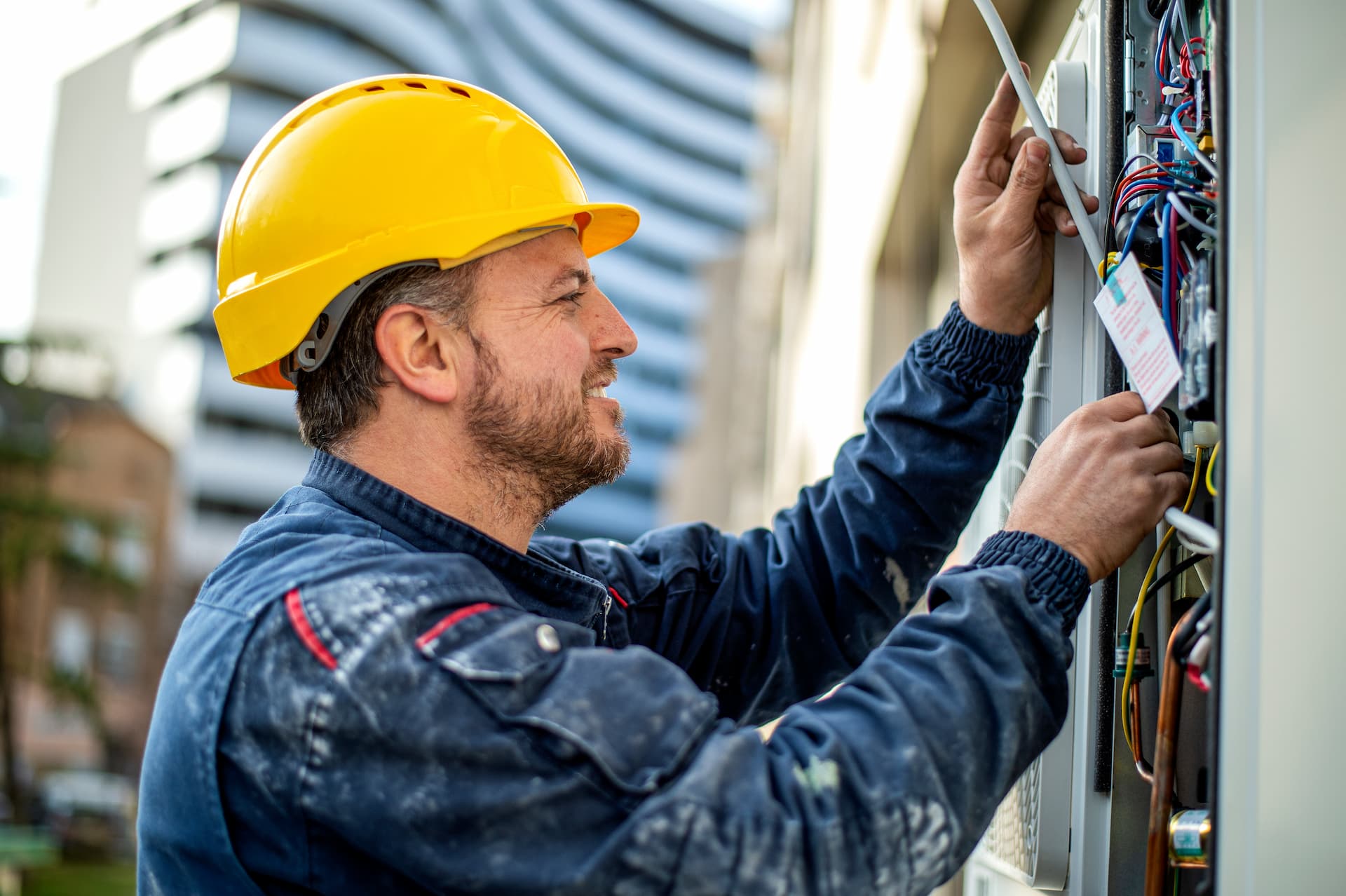 Electrician with yellow hard hat examining electrical box