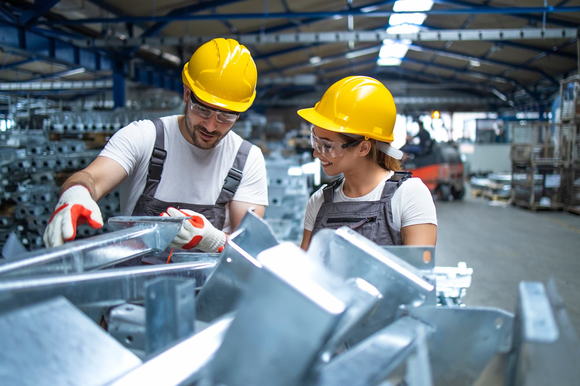 Two contractors in manufacturing warehouse examining steel beams