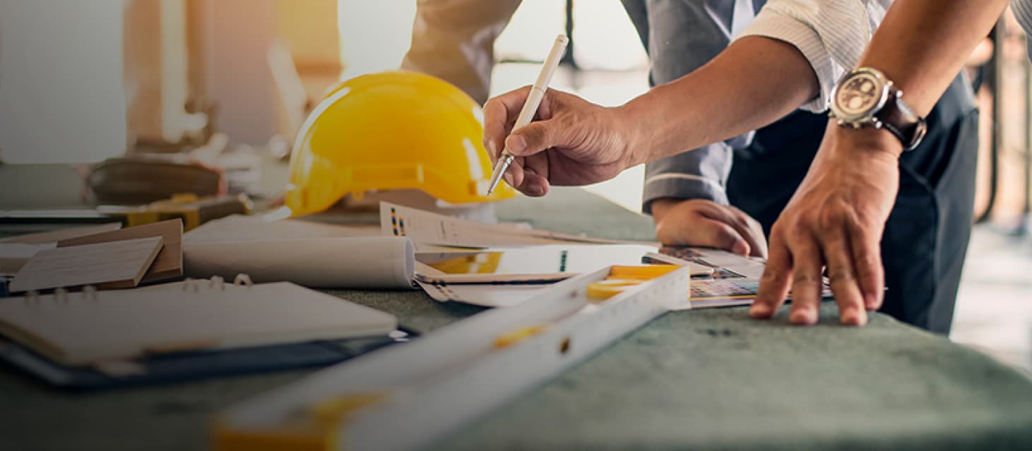 Two subcontractors leaning on table reviewing construction documents
